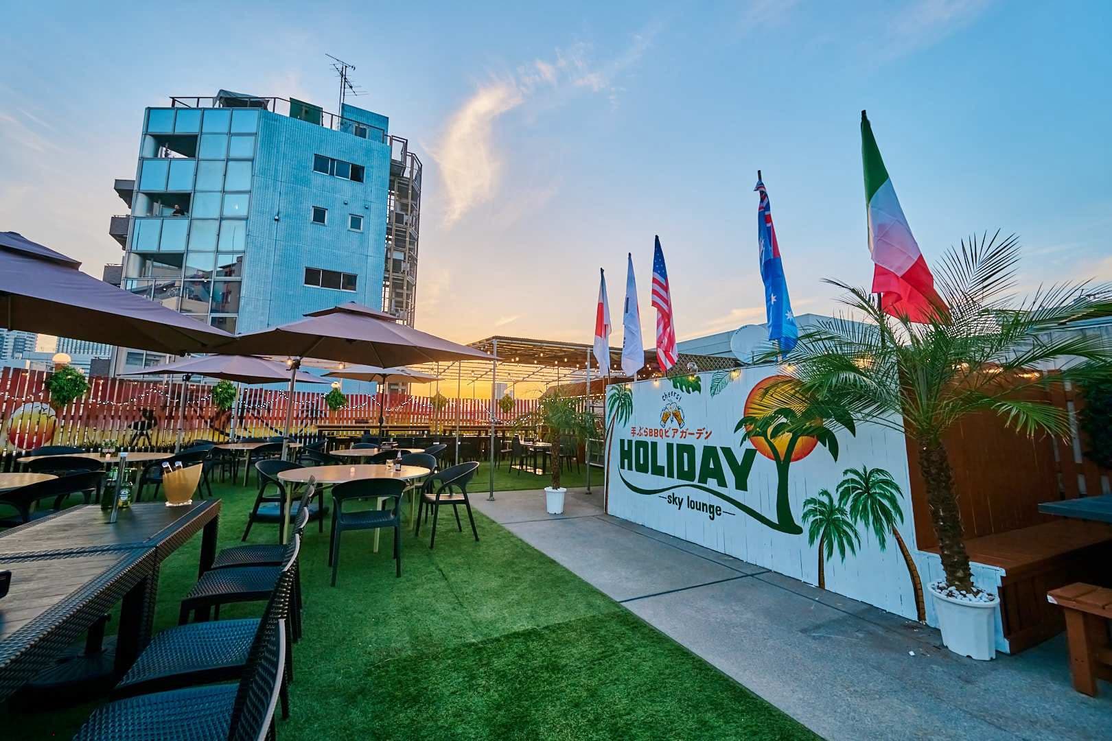 夕暮れの空とヤシの木、HOLIDAYのサインが並ぶテラス